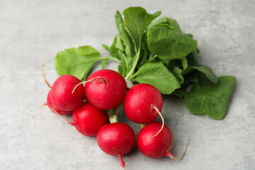 Bunch of fresh radishes on light grey table, closeup