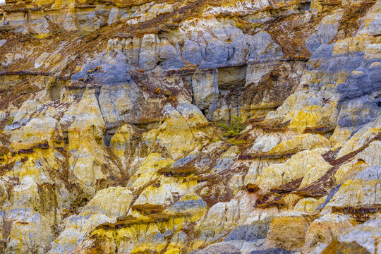 View of earth showcasing contrasting layers of brown, yellow, and bluish-gray rock formations, a geological tapestry etched by time, Shetpe, Mangystau Region, Kazakhstan.
