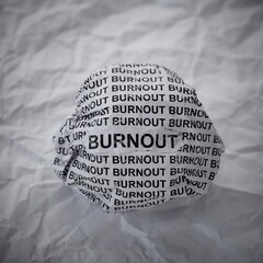 Crumpled paper ball with words Burnout on crumpled white paper background. Close-up
