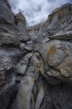 View of stark, layered rock formations under a stormy sky create a dramatic, textured landscape that speaks of ancient geological forces, Shetpe, Mangystau Region, Kazakhstan.