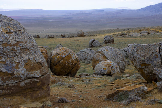 View of spherical rocks scattered across the arid landscape under a muted sky, creating a surreal, earthy tableau, Shetpe, Mangystau Region, Kazakhstan.