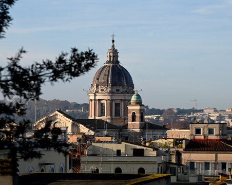 Elevated view across the rooftops of Rome, Italy, featuring the domes of historic churches illuminated by warm evening light. The timeless skyline showcases the Eternal City's remarkable blend of Rena