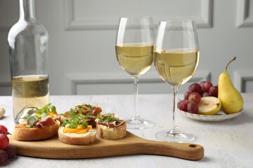 Tasty bruschettas with prosciutto and wine served on white table, closeup