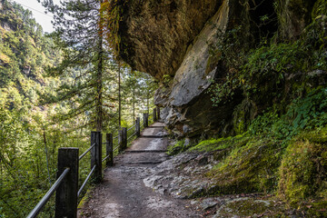 A wide paved route with railings under the big stone in Himalaya mountains. Everest base camp trek, Nepal.