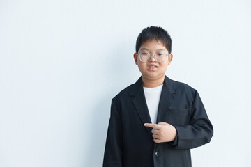 A chubby Asian boy in a suit is pointing to the side in the blank space for text.