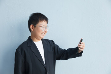 An Asian boy in a business suit is taking a selfie with space left for text.