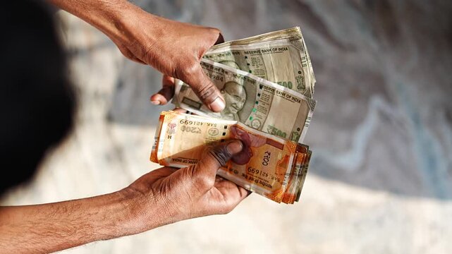 Man counting Indian rupee notes placed on table, representing financial calculation, income, and cash flow.