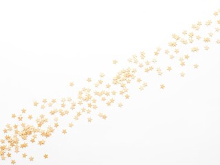 Scattered small golden starshaped confetti or sprinkles forming a diagonal line isolated on white background
