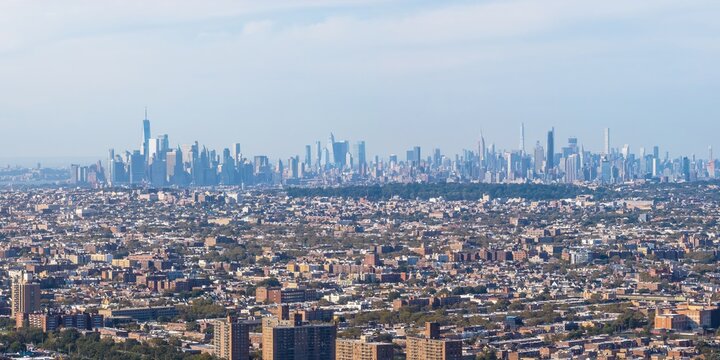 Aerial view of dense urban sprawl gives way to a distant skyline punctuated by towering skyscrapers, Brooklyn, New York, United States.