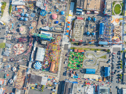 Aerial view of a vibrant amusement park with roller coasters and colorful attractions, a tapestry of joy and excitement, Brooklyn, New York, United States.