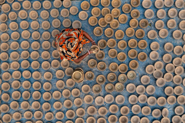 Bogura, Bangladesh - 27 January 2020: Aerial view of a woman in a vibrant orange patterned shawl amidst rows of clay pottery, crafting with earthen tones.