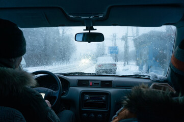 Driver and passenger in a car with wet snow and rain splattered on the windshield. A trip on a gloomy winter day.