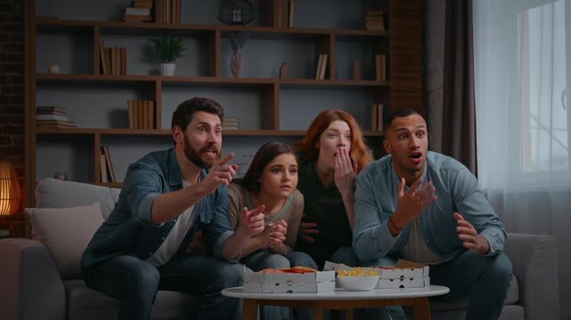 Happy four multiethnic friends supporting television sport team win champions applauding cheering men women at home party watching tv football fans spectators soccer game celebrating yelling together