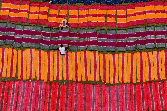 Narayanganj, Bangladesh - 29 January 2020: Aerial view of vibrant fabrics laid out in neat rows, their rich hues creating a striking geometric pattern on the ground.