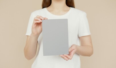 A woman in a white t-shirt holding a blank gray card