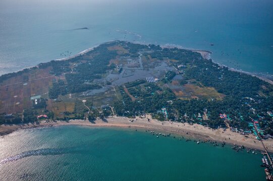 Aerial view of a sandy beach meeting the turquoise sea, the island covered in vegetation, creating a contrast with the blue waters, Cox's Bazar, Chittagong Division, Bangladesh.