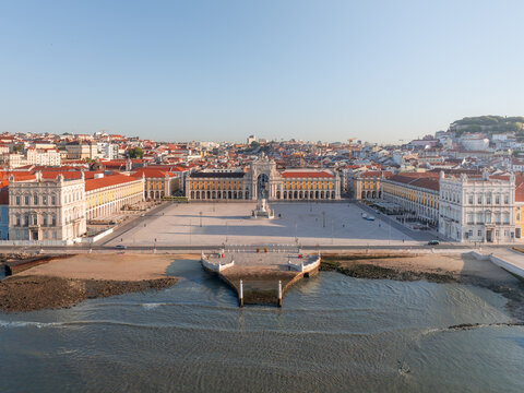 Aerial view of the Terreiro do Paco reflects in the tranquil waters as the city unfolds in a tapestry of terracotta rooftops and pale facades, Lisbon, Lisbon, Portugal.