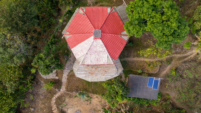 Aerial view of a vibrant red and white hexagonal rooftop amidst dense green foliage, a unique structure standing out in the landscape, Lake Atitlan, Solol&aacute; Department, Guatemala.