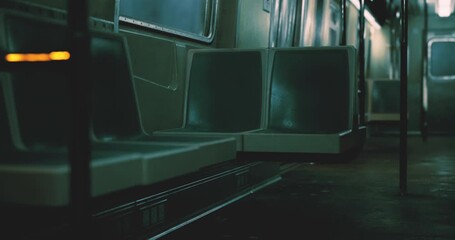 An empty subway car features darkened seats and soft, dim lighting, creating a calm atmosphere late at night. The absence of passengers enhances the stillness.