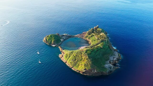 Coastal volcanic islet with bright lagoon water contrasting with dark outer ocean on Sao Miguel island, Azores, drone footage