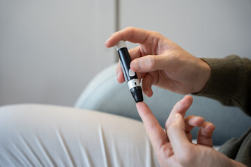 Adult performing a blood glucose test using a lancet