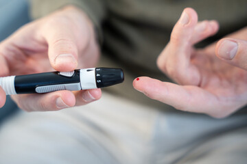Fototapeta premium Person checking blood glucose level with lancet