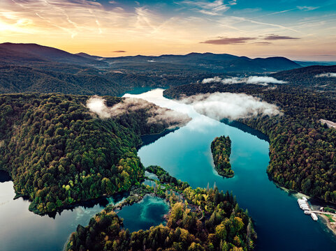 Aerial view of the turquoise Plitvice Lakes National Park, with lush forests reflecting in the clear water under a pastel sky, Plitvicka Jezera, Lika-Senj County, Croatia.