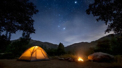 Illuminated camping tent and campfire under a starry mountain night sky