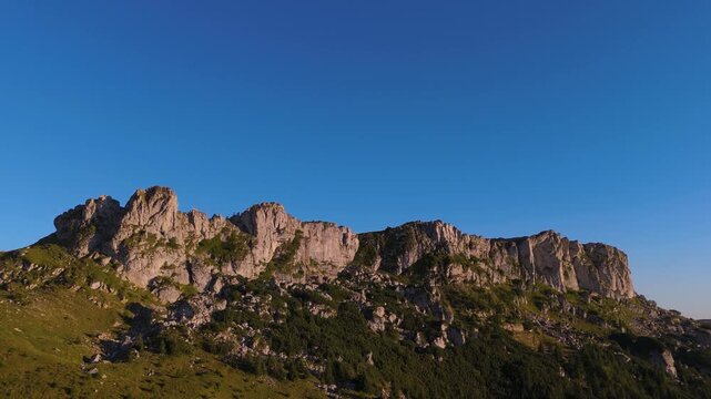 Slow Motion Aerial Pull Away from Strungile Mici Ridge in Bucegi Mountains at Golden Hour with Deep Blue Copy Space