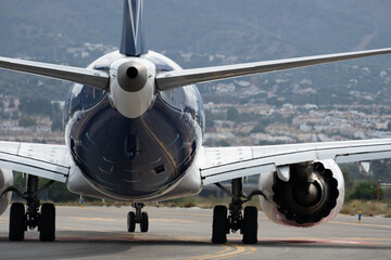 Commercial airplane on runway with mountainous backdrop