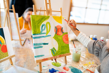 Child painting during art workshop with mother