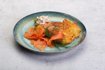 Kartoffelpuffer mit Lachsstreifen auf einem blauen Teller