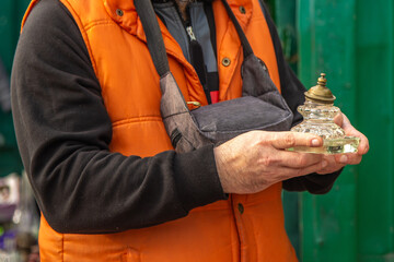 Male hands holding a glass inkwell with metal lid at a flea market