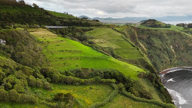 Green agricultural and natural vegetation stretching over volcanic sea cliffs on Sao Miguel Island, Azores