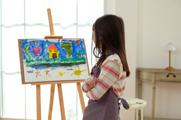 Child Creates Art While Standing at an Easel in a Bright Room During Daytime