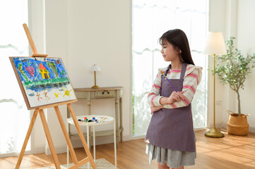 Child Creates Art While Standing at an Easel in a Bright Room During Daytime