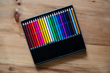 Packet of color pencils on wooden surface.