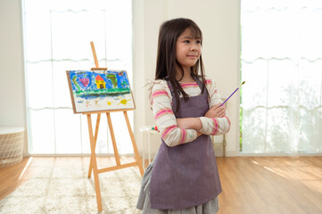 Child Creates Art While Standing at an Easel in a Bright Room During Daytime