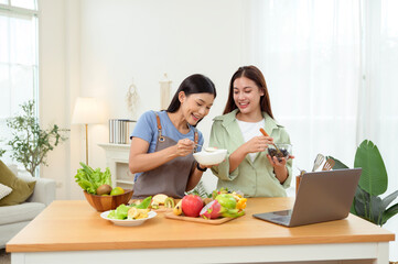 Friends Preparing a Healthy Meal Together in a Bright Kitchen While Using a Laptop for Recipes