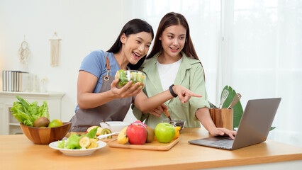 Friends Preparing a Healthy Meal Together in a Bright Kitchen While Using a Laptop for Recipes