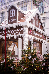 A gingerbread house and a Christmas tree A Christmas tree decorated with gingerbread men and red bows on the city streets

