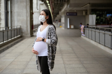 Pregnant woman wearing protective mask outdoors, health and maternity concept.