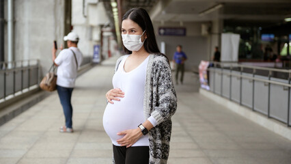Pregnant woman wearing protective mask outdoors, health and maternity concept.