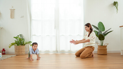 Boy Takes His First Steps at Home While Holding His Mother's Hand in a Warm Living Room Setting