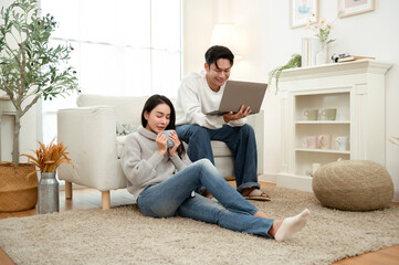Couple Relaxing at Home in Winter While Using a Laptop and Enjoying Drinks Together