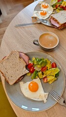 Plate with fried egg sandwich fresh salad and coffee served on a wooden table in a cozy cafe interior. The image represents balanced breakfast routine relaxed dining and healthy morning lifestyle