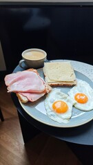 Plate with fried egg ham cheese sandwich and coffee served on a small table in a cozy cafe setting. The image represents classic breakfast routine, comfort food, and relaxed morning lifestyle