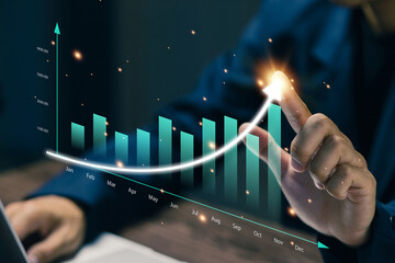 A professional points at a rising business chart showing monthly performance growth, representing financial success, revenue increase, strategic planning, KPI analysis, and corporate forecasting.