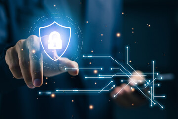 A professional touches a digital shield with a lock icon, representing cybersecurity protection, secure networks, data privacy, encryption systems, and enterprise IT security management.