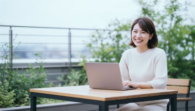 緑豊かな屋外テラス席でパソコン作業をする女性